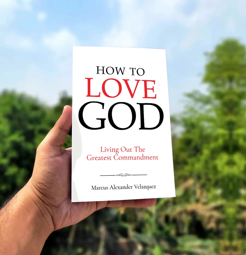Paperback copy of How To Love God held in a hand outdoors